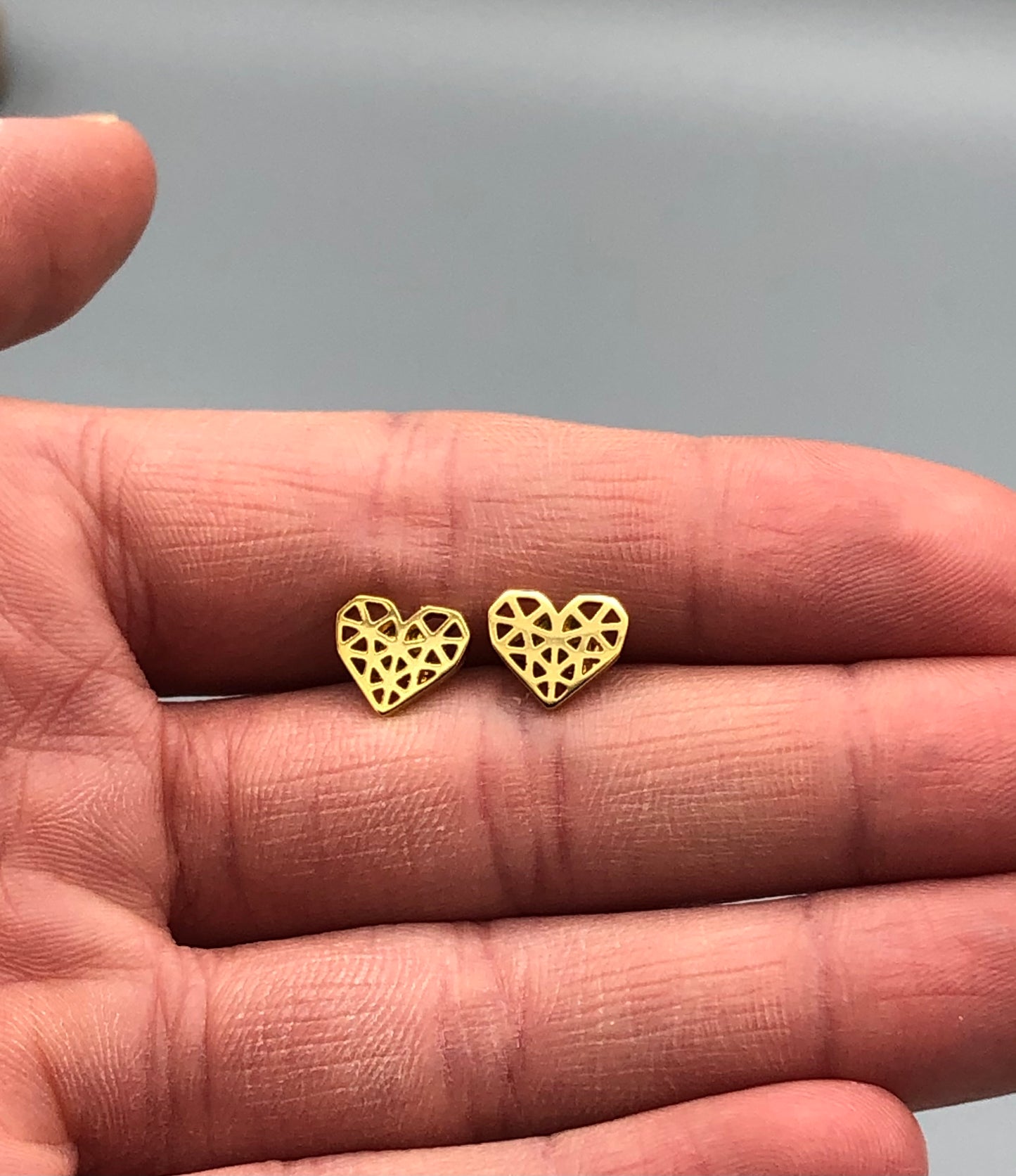 Gold Stainless Steel Heart Earrings held in hand for size reference